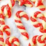 Red and white Candy Cane Cookies spread out on a white marble table top