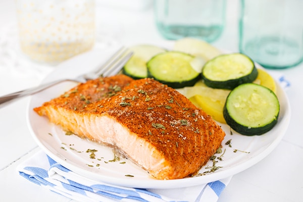 horizontal image of Easy Creole Salmon on white plate with veggies