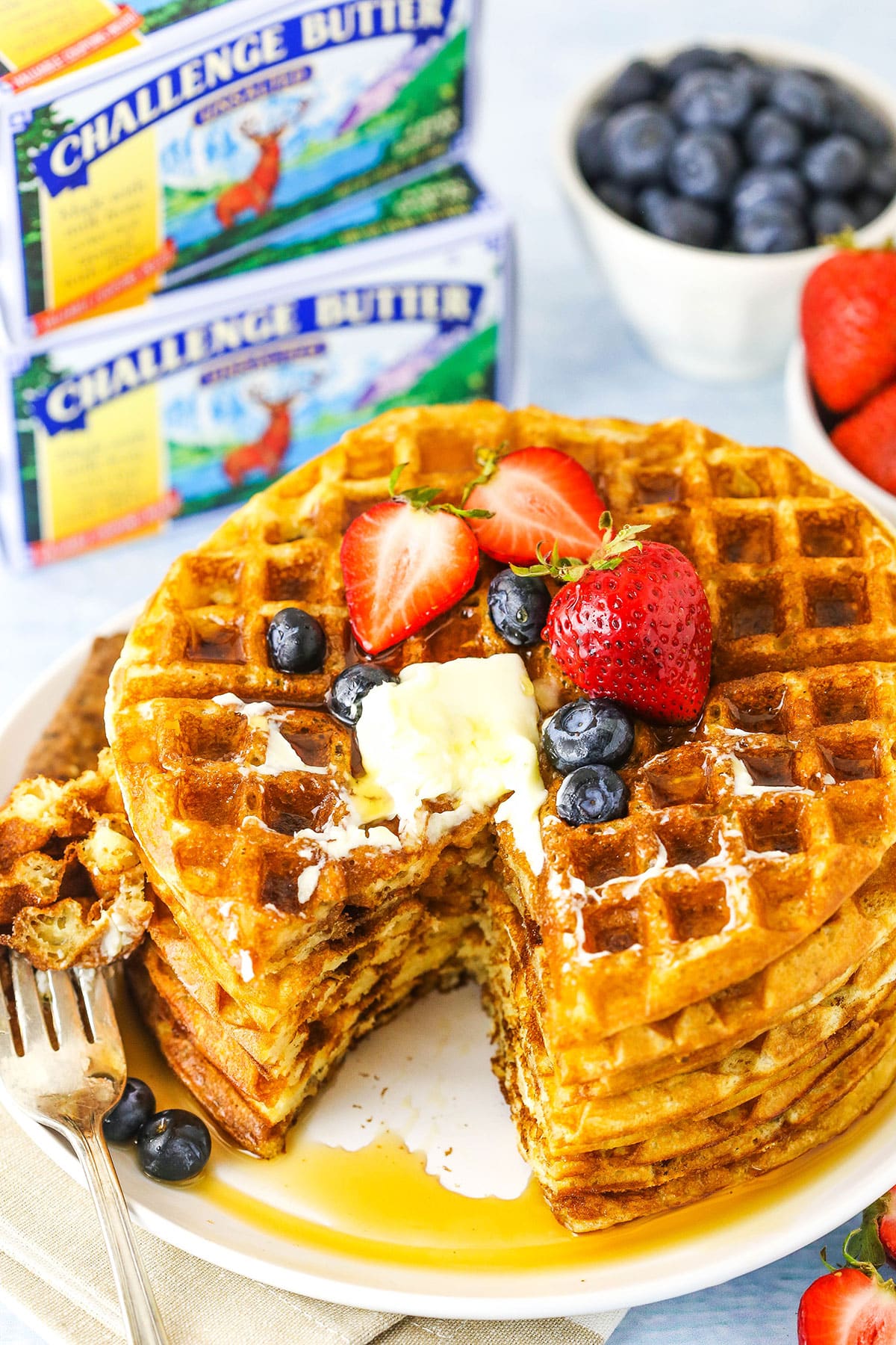 stack of waffles with a bite and challenge butter in background