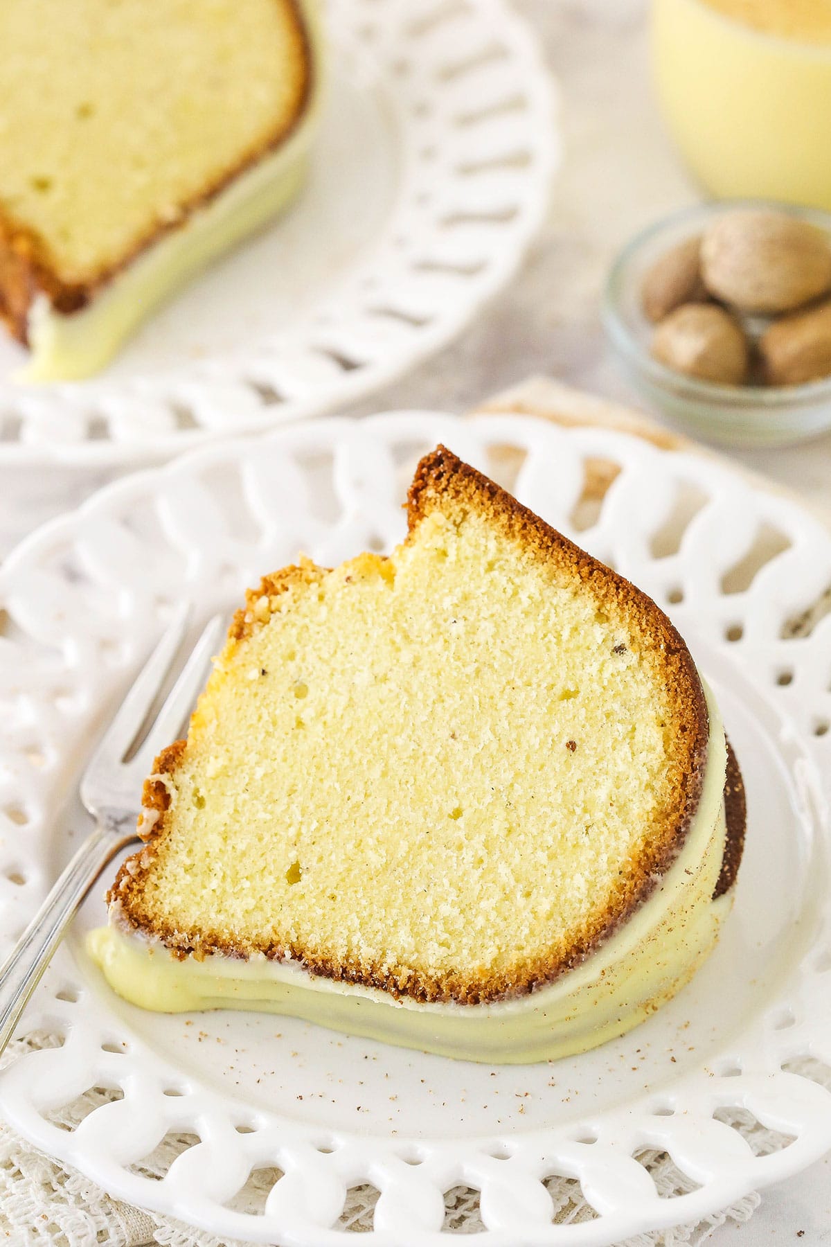 A slice of eggnog pound cake with eggnog glaze on a plate with cut-outs decorating the rim