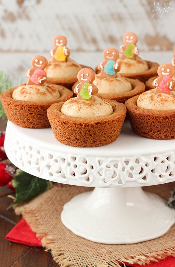 Gingerbread Cheesecake Cookie Cups topped with mini gingerbread cookies on a white cake stand