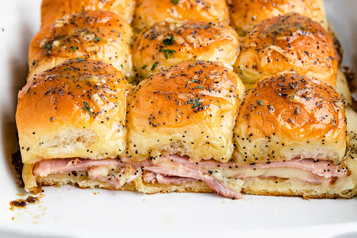 A baking dish full of freshly baked ham and cheese sliders