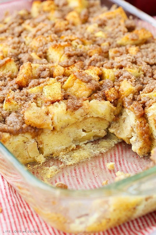 Apple French Toast Casserole with a serving missing in a glass baking pan