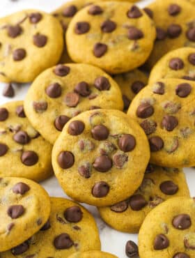 a scattered pile of pumpkin chocolate chip cookies on marble countertop
