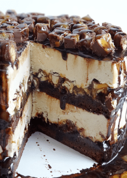 A Snickers Brownie Ice Cream Cake on a Cake Stand with a Slice Missing